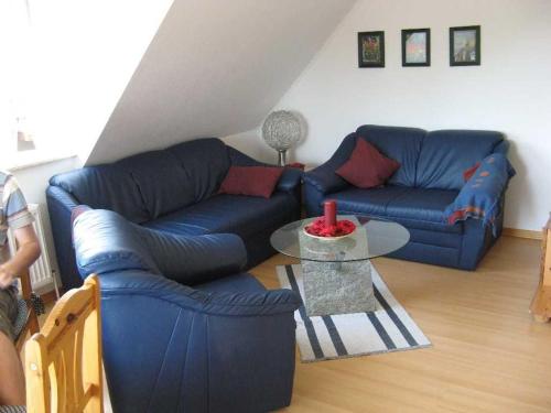 uma sala de estar com dois sofás azuis e uma mesa em Ferienwohnung Schwalbennest em Carolinensiel