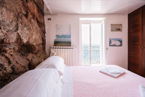 Un dormitorio con una cama blanca y una pared de piedra. en Tellaro, Casa "La Terra" - accesso privato al mare, en Tellaro