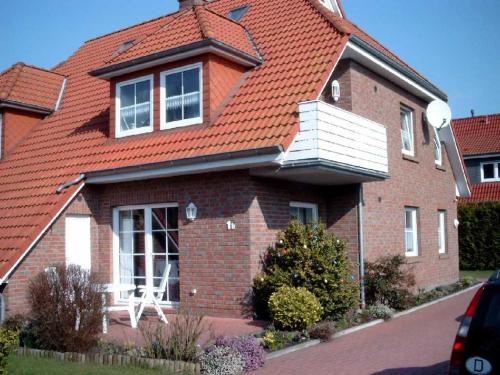 uma casa com um telhado laranja com uma mesa branca na janela em Ferienwohnung Schwalbennest em Carolinensiel