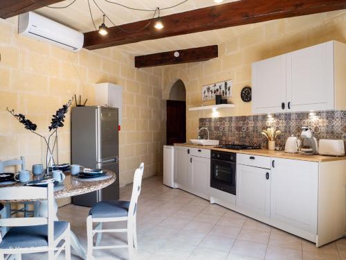 a kitchen with white cabinets and a table with chairs at IL Gnejna II in Xagħra