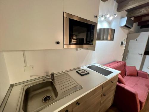 eine Küche mit einem Waschbecken und einem roten Sofa in der Unterkunft 67 Rooms in Cefalú