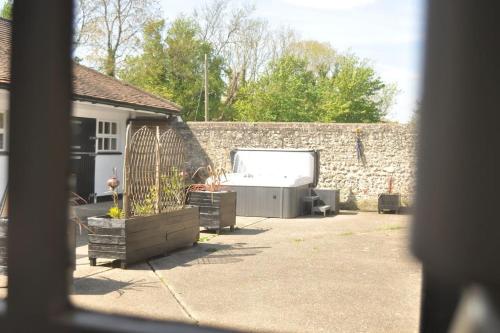 einen Hinterhof mit einer Steinmauer und einer Badewanne in der Unterkunft Chillout!! Sussex Flint Cottage- HotTub - Goodwood in Eartham