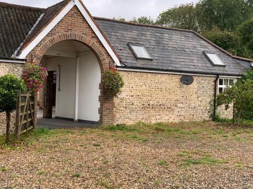 ein Backsteinhaus mit einem Torbogen im Hof in der Unterkunft Chillout!! Sussex Flint Cottage- HotTub - Goodwood in Eartham