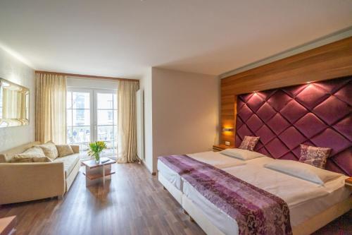 ein Hotelzimmer mit einem großen Bett und einem Sofa in der Unterkunft Arkona Strandresidenzen in Binz