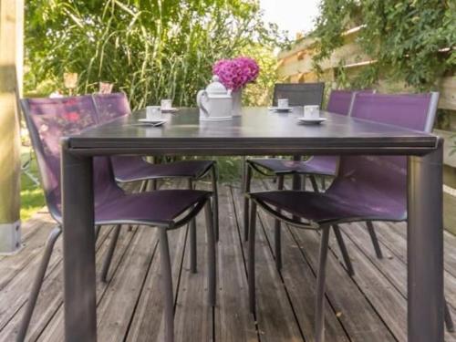 une table noire et des chaises violettes sur une terrasse dans l'établissement Charmante maison rénovée à 300m de la Loire avec jardin, terrasse, WiFi et équipements bébé - FR-1-306-815, à Saint-Julien-de-Concelles