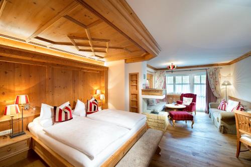 a bedroom with a large bed and a living room at Hotel Alpin Spa Tuxerhof in Tux