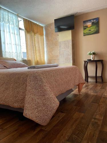 um quarto com uma cama grande e piso em madeira em Hospedaje Baños de Agua Santa em Baños