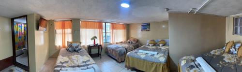 um pequeno quarto com 2 camas e uma janela em Hospedaje Baños de Agua Santa em Baños