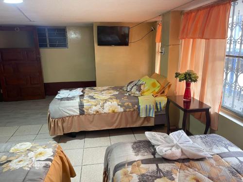 um quarto de hotel com duas camas e uma televisão em Hospedaje Baños de Agua Santa em Baños