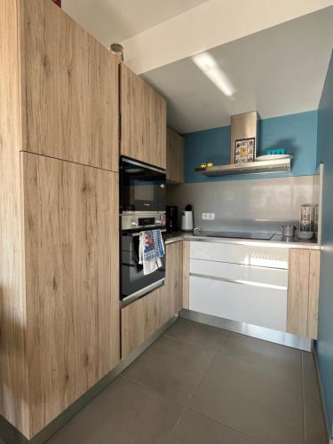 uma cozinha com armários de madeira e um forno com placa de fogão em vue mer-garage-500m port et plage em Sanary-sur-Mer