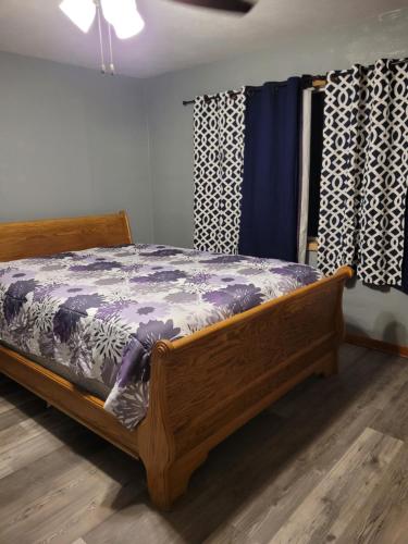 een slaapkamer met een houten bed en gordijnen bij Travelers Guesthouse in Greenfield