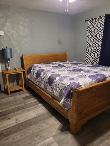 a bedroom with a wooden bed with a purple comforter at Travelers Guesthouse in Greenfield