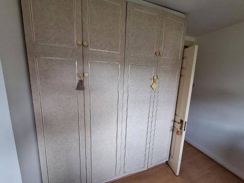 a closet with white cabinets in a room at Spacious double bedroom in quiet house with garden view in Dublin