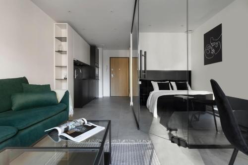 a living room with a green couch and a bed at Elite Apartments Wałowa Studio in Gdańsk