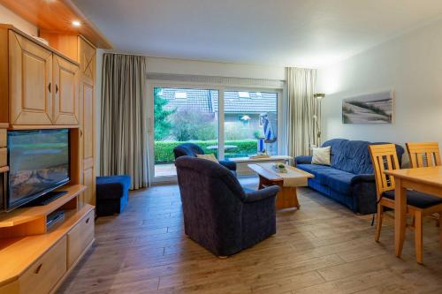 ein Wohnzimmer mit einem blauen Sofa und einem TV in der Unterkunft Wohnen am Südstrand 02 in Wyk auf Föhr