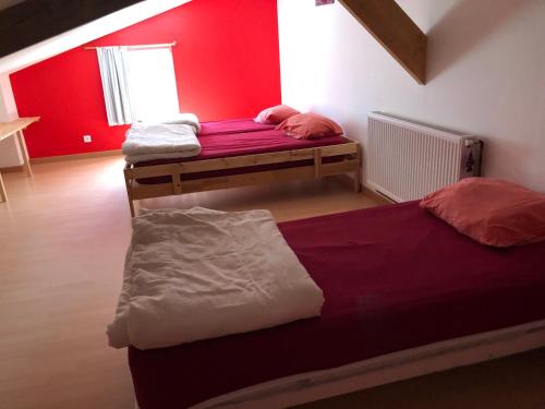 2 camas en una habitación con una pared roja en Gîte Saint-Léonard-des-Bois, 8 pièces, 15 personnes - FR-1-410-224, en Saint-Léonard-des-Bois