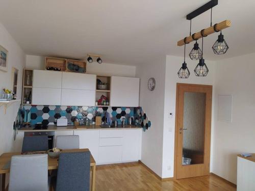 a kitchen with white cabinets and a table in a room at Apratmán Julie – Bavorská Ruda in Bayerisch Eisenstein