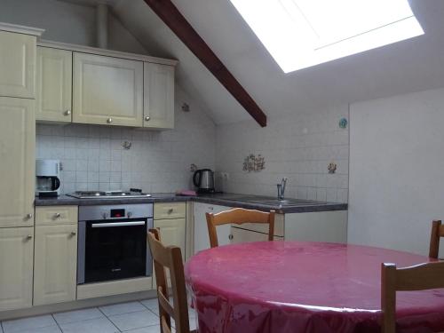 a kitchen with a table with a pink table cloth at Gîte familial avec jardin et vélos, proche Le Mans - FR-1-410-146 in Saint-Gervais en-Belin