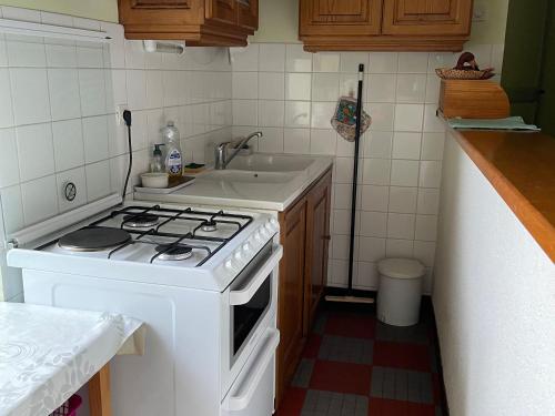 Il comprend une cuisine équipée d'une cuisinière blanche et d'un évier. dans l'établissement Charmante Fermette Rénovée avec Terrasse Privative et Vélos, 2 Chambres, Proche Le Lude - FR-1-410-155, à La Chapelle-aux-Choux