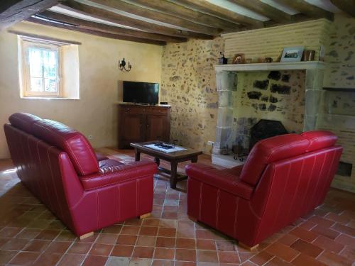 - un salon avec deux chaises rouges et une cheminée dans l'établissement Charmante maison paysanne rénovée avec grand terrain, proche de la rivière et du village médiéval - FR-1-410-162, à Asnières-sur-Vègre