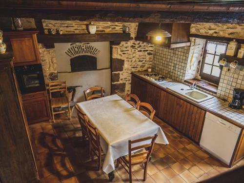 une cuisine avec une table et des chaises dans une pièce dans l'établissement Maison Rivière avec Terrasse, Wifi et Jardin Fleuri - Idéal Pêcheurs - FR-1-410-168, à Rouez