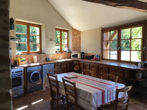 une cuisine avec une table et une cuisinière four supérieur dans l'établissement Gîte de charme rénové avec jardin, vélos et activités près de la Sarthe - FR-1-410-191, à Souvigné-sur-Sarthe