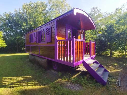 un wagon-train violet garé dans un champ dans l'établissement Séjour Bucolique en Roulotte au Cœur d'une Ferme Familiale en Sarthe - FR-1-410-229, à Chantenay-Villedieu
