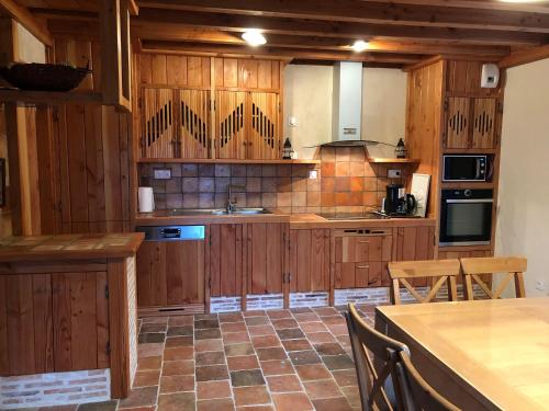 a kitchen with wooden cabinets and a table and chairs at Gîte familial restauré en pleine nature avec terrasse, proche forêt, idéal pour groupes et PMR - FR-1-410-255 in Chemiré-en-Charnie