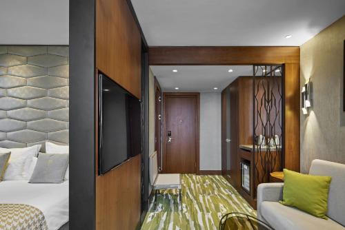 a room with a bed and a couch and a television at TITANIC Chaussee Berlin in Berlin