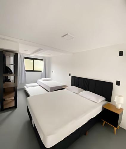 two beds in a bedroom with white walls at Lofts Meia Morada SFS in São Francisco do Sul