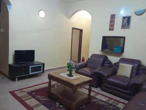 a living room with a couch and a table at Fayes Apartments in Brusubi