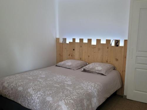 um quarto com uma cama com uma cabeceira em madeira e 2 almofadas em Gîte Louplande, 1 pièce, 4 personnes - FR-1-410-364 em Louplande