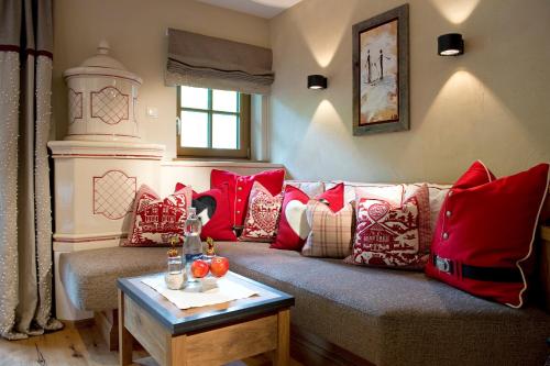 a living room with a couch with red pillows at Hotel Alpin Spa Tuxerhof in Tux