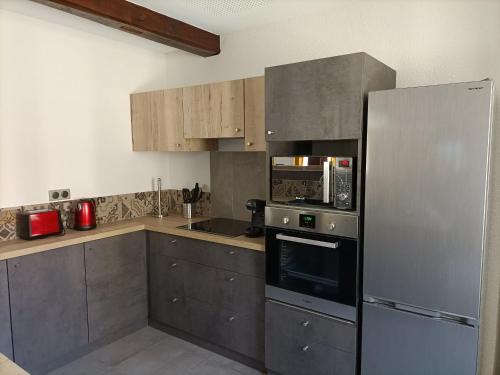 une cuisine avec un réfrigérateur et des armoires en acier inoxydable dans l'établissement Gîte haut de gamme face à l'abbaye de Noirlac - 5 ch, 5 sdb, clim, terrasse privée - FR-1-586-26, à Bruère-Allichamps