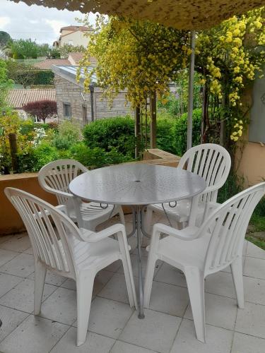 une table blanche et quatre chaises sous un parasol dans l'établissement Chez Anne et Aimé, à Millau