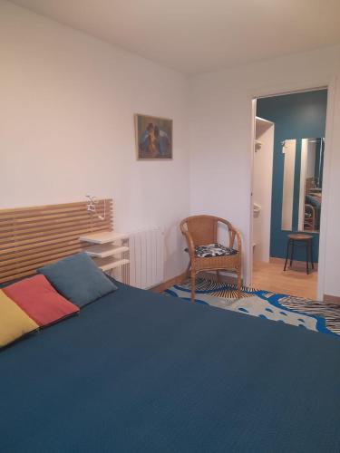 - une chambre avec un lit bleu et une chaise dans l'établissement Chez Anne et Aimé, à Millau