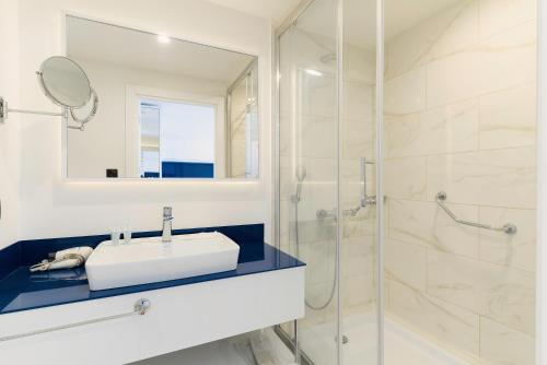 a white bathroom with a sink and a shower at Batumi Sea View in Batumi
