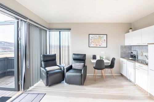 a kitchen with two black chairs and a table at Lax&aacute;rdalur Cabin in Einarssta&eth;ir
