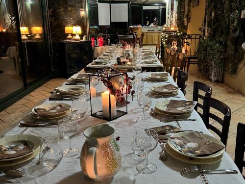 une grande table avec des assiettes, des verres et une bougie dans l'établissement Retraite paisible avec cheminée, étang privé et chalet près du Mans - FR-1-410-382, à Dehault