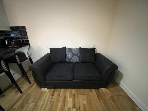 a black couch in a living room with wooden floors at 1 Bedroom Flat with Parking in Leicester