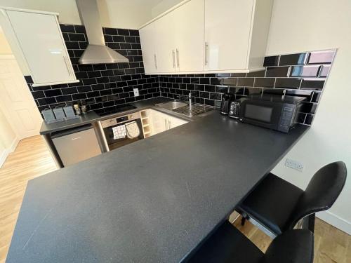 a kitchen with white cabinets and a black counter top at 1 Bedroom Flat with Parking in Leicester