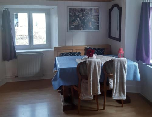 a dining room with a blue table with chairs and a window at Au Grizz in Tramelan