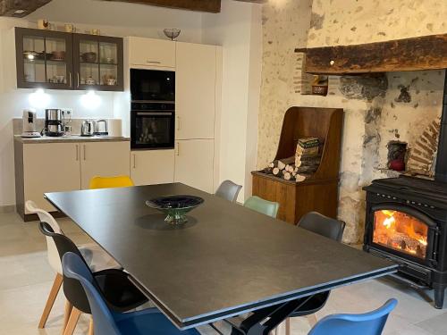 une salle à manger avec une table et une cheminée dans l'établissement Gîte de charme près du Mans, tout équipé avec espace extérieur, garage, et confort moderne - FR-1-410-385, à La Bosse