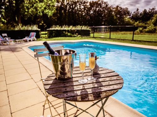 - une table avec des verres de champagne et un seau à côté de la piscine dans l'établissement Grand Château Renaissance avec Parc, Piscine et Activités, Rénové en 2023 - FR-1-410-389, à Vallon-sur-Gée