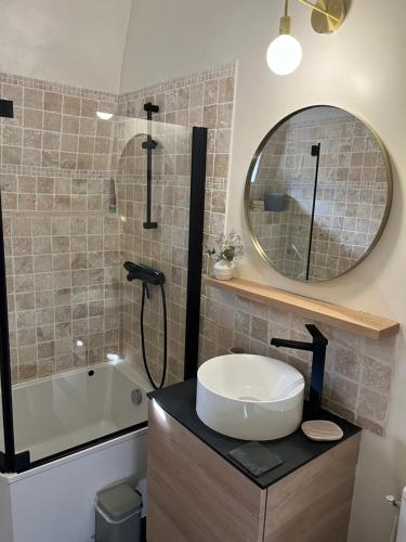 une salle de bain avec un lavabo, une baignoire et un miroir dans l'établissement La Genette, à La Rochelle
