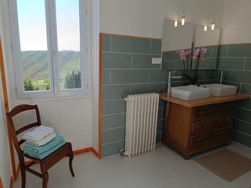 a bathroom with a sink and a mirror and a chair at Maison d'HÔTES LA FEZENDES in Miradoux