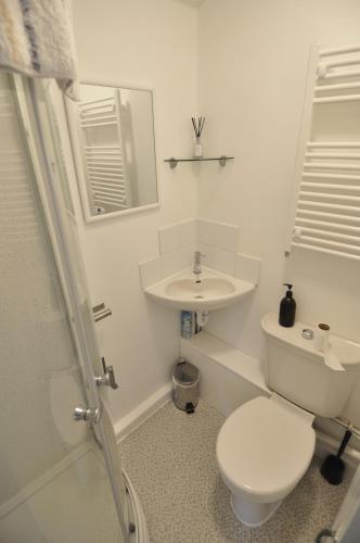 a white bathroom with a toilet and a sink at Fistral Studio in Newquay