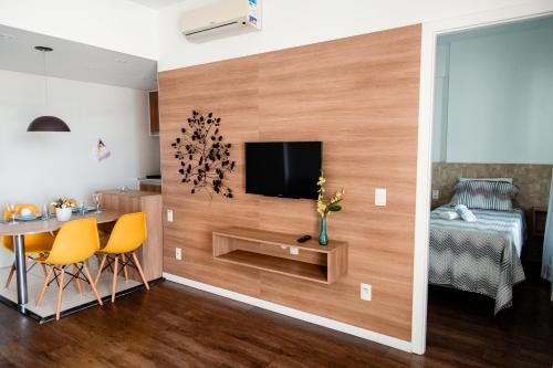 sala de estar con TV, mesa y cama en Mondial Apartments By BnbHost, en Salvador