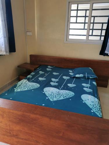 a bed with a blue comforter on top of it at PROSPERITY in Sambava
