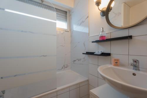 ein weißes Badezimmer mit einer Badewanne und einem Waschbecken in der Unterkunft MUL HOUSE in Mulhouse